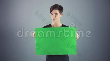 年轻男子穿着黑色衬衫，手持绿色钥匙片<strong>海报</strong>，<strong>灰色背景</strong>